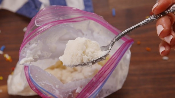 Ice cream in a plastic Ziploc bag with a spoon dipped inside.