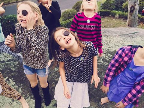 Group of children standing and trying to catch falling Oreo cookies in their mouths without using their hands.