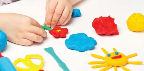 Small hands work to make different fun shapes out of Play Doh.