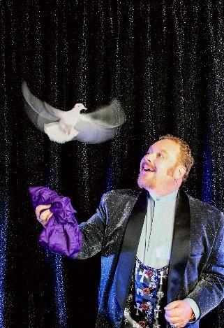 Magician John Measner watches a dove fly out of a purple scarf.