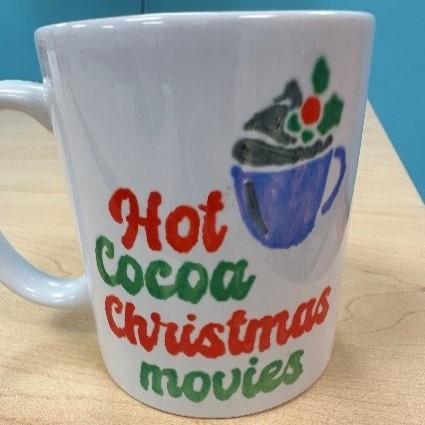 White mug with design of a festive mug and text reading "Hot cocoa Christmas movies" 