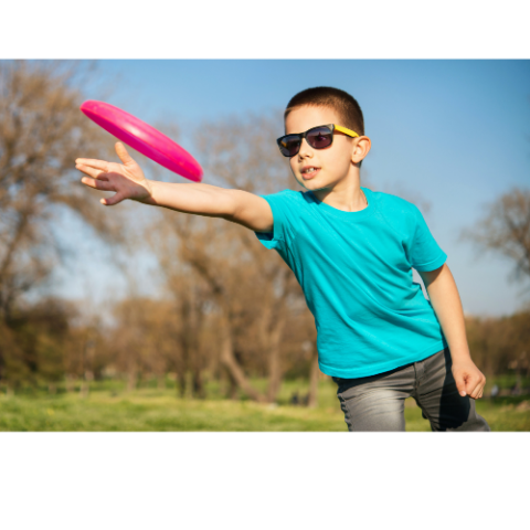 Photo of a young boy throwing a frisbee outside.