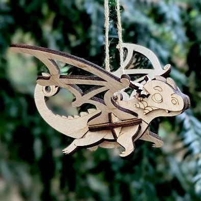 Photo of a wooden dragon hanging from a string against a leafy background.