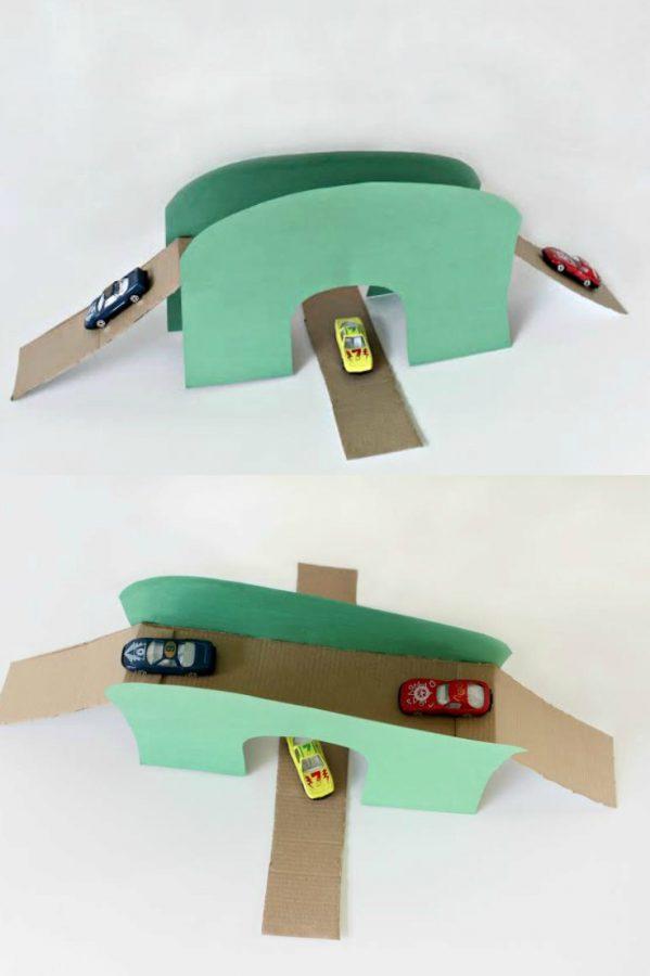 Two cardboard bridges with toy cars on them sit on a white table.