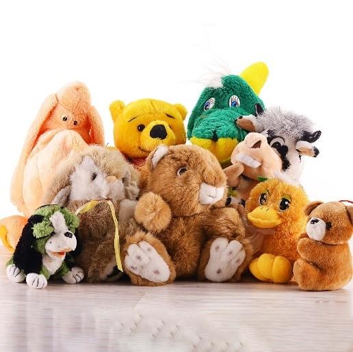 A bunch of stuffed animals sit grouped together on a gray table.