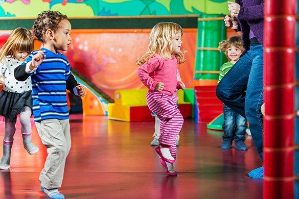 Toddlers dancing in a colorful room.