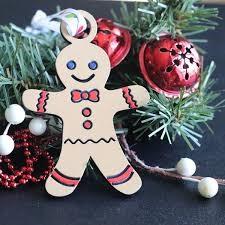 A wooden gingerbread ornament hangs on a Christmas tree, surrounded by festive decorations.